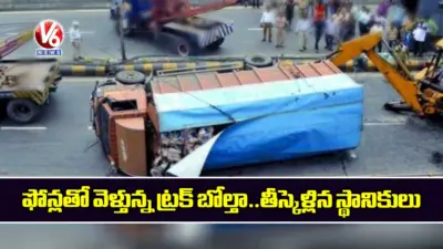 ఫోన్లతో వెళ్తున్న ట్రక్ బోల్తా..తీస్కెళ్లిన స్థానికులు